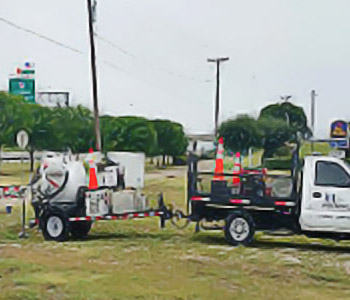 truck with an attached trailer with caution cones in the truck bed and on the equipment in the trailer